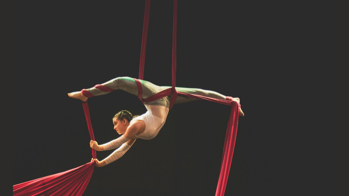 Corso tessuti aerei Monza — figura sospesa su tessuto rosso aerial silk